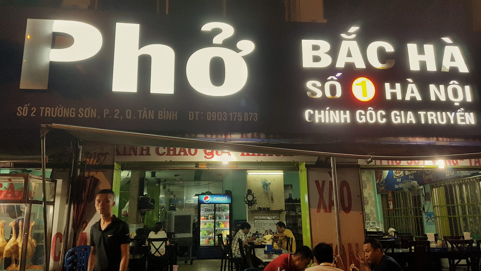 Guests dining inside the warmly lit Phở Phố restaurant at night